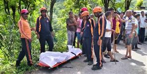 woman collecting grass swept away in water stream