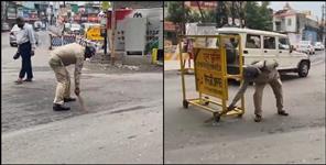 image: Policeman sweeps the road in Dehradun