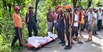 woman collecting grass swept away in water stream